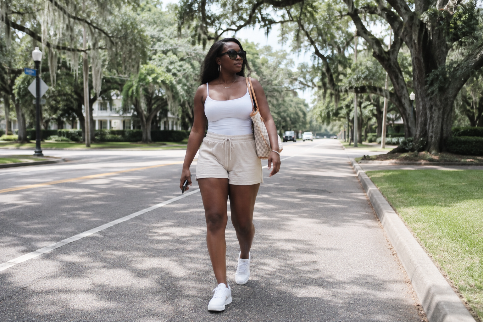 A woman walking along a tree-lined residential street